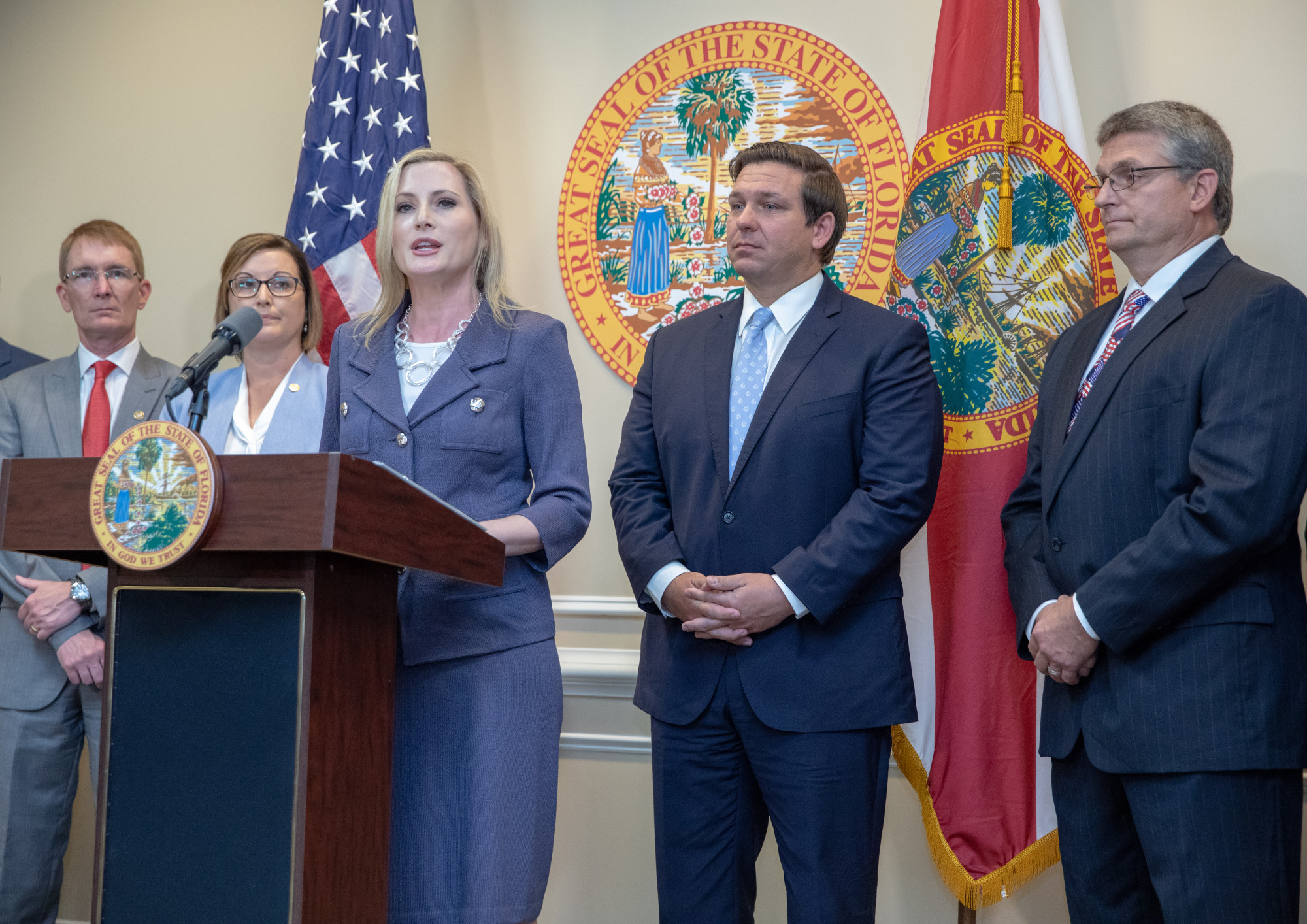 Laurel Lee at press conference with Governor DeSantis in background with others